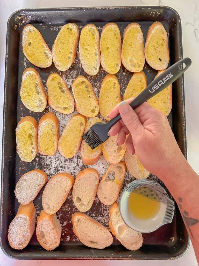 brushing olive oil on the crostini