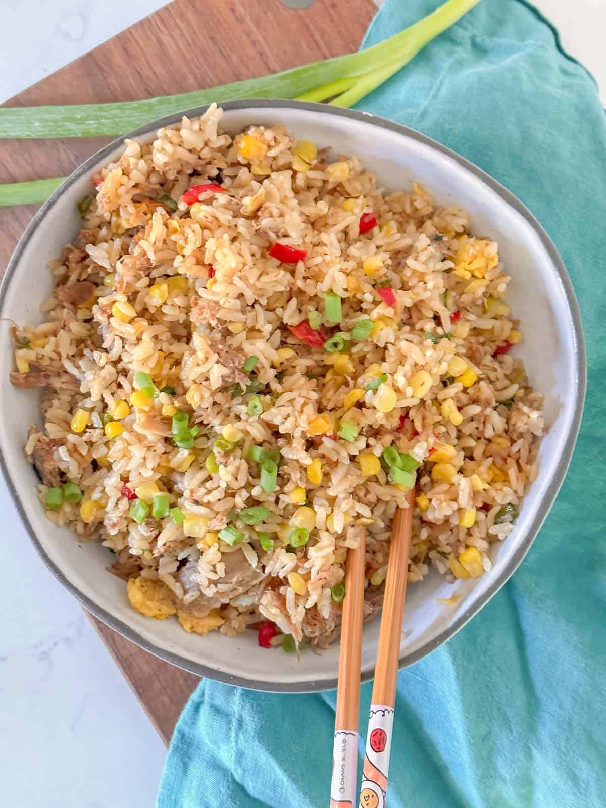 hawaiian pork fried rice in a bowl with chopsticks. made with shredded kalua pork