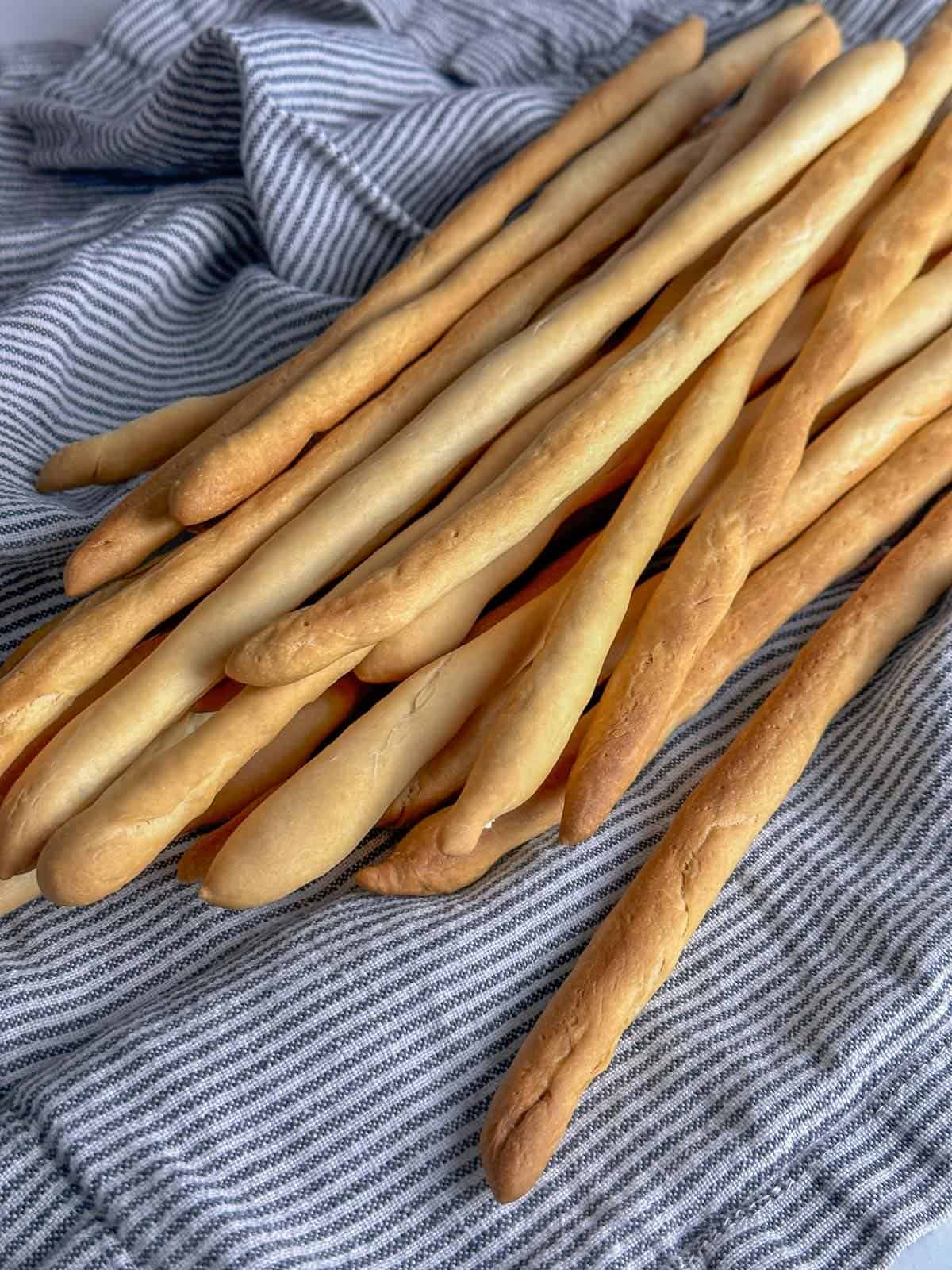 a freshly baked of homemade grissini on a striped kitchen towel