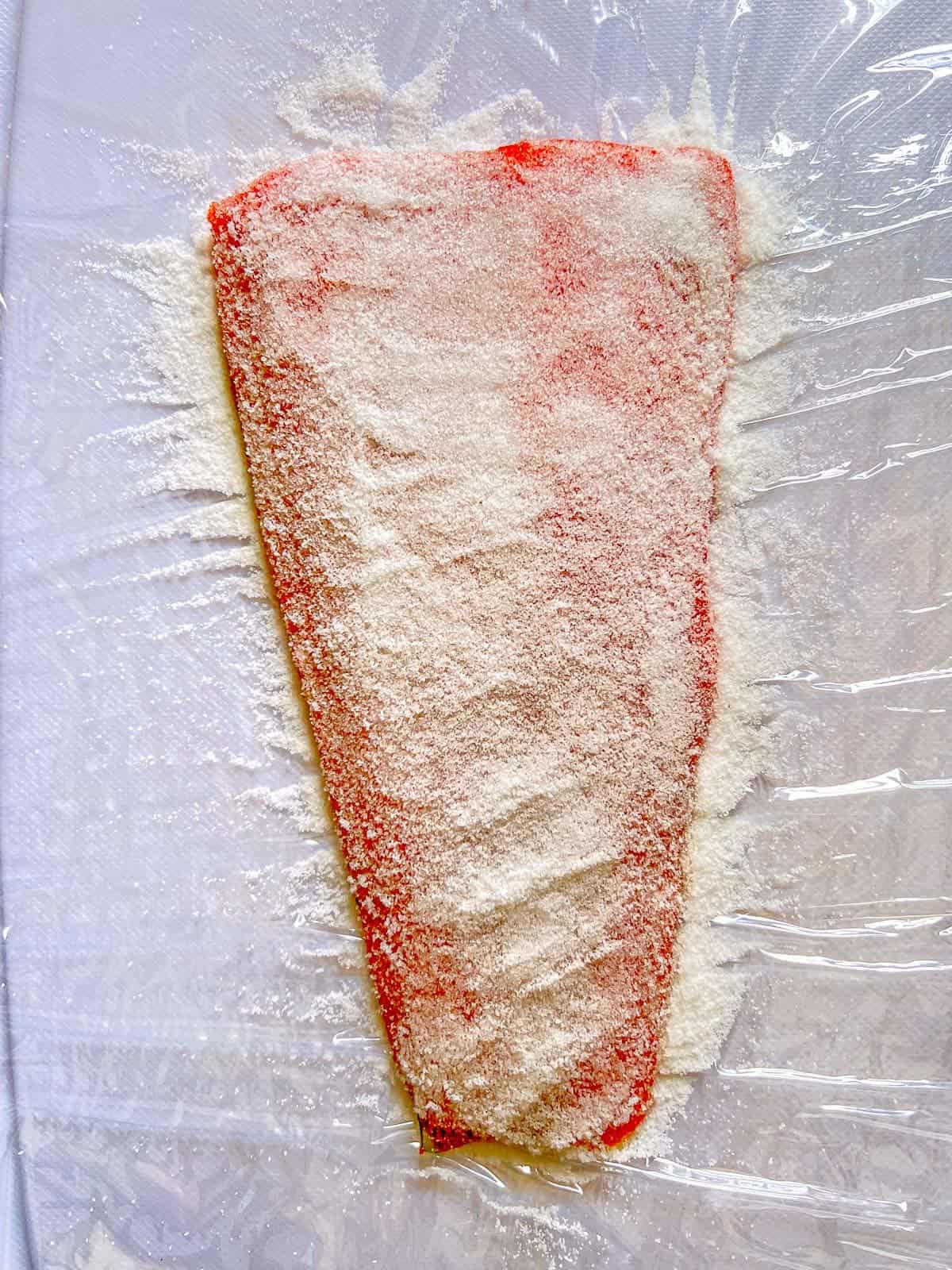 To make salt cured salmon sprinkle a salmon fillet with salt and sugar, and then wrap it tightly in plastic wrap