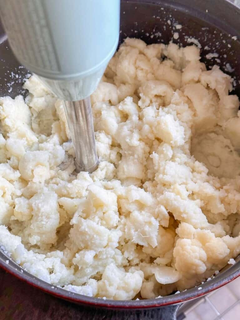 an immersion blender is used to puree the cauliflower