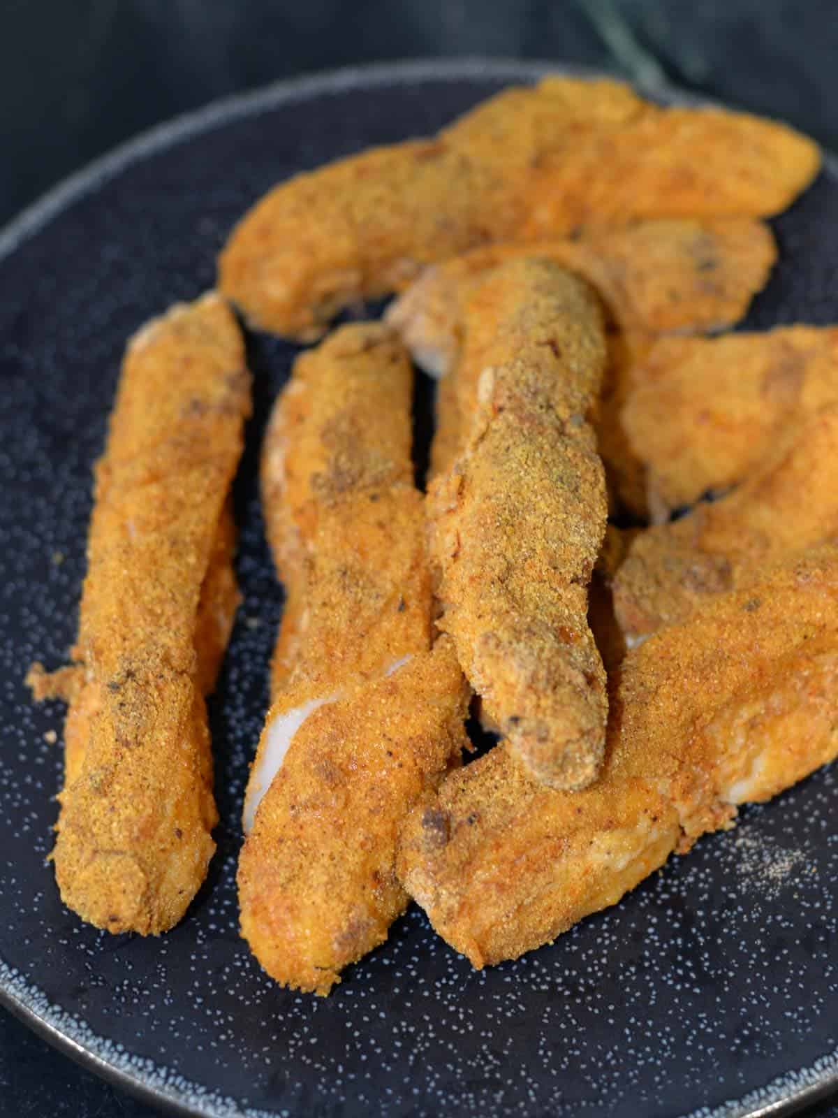 cooked breaded fish on a black plate, ready to make fish tacos