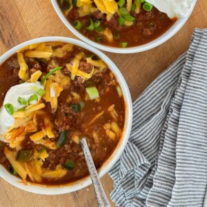 keto chili in a white bowl topped with sour cream, and onions