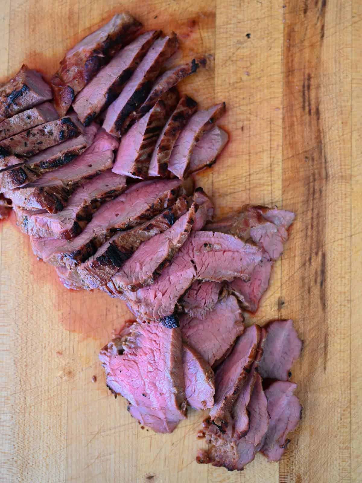 medium rare tri tip sliced on a cutting board