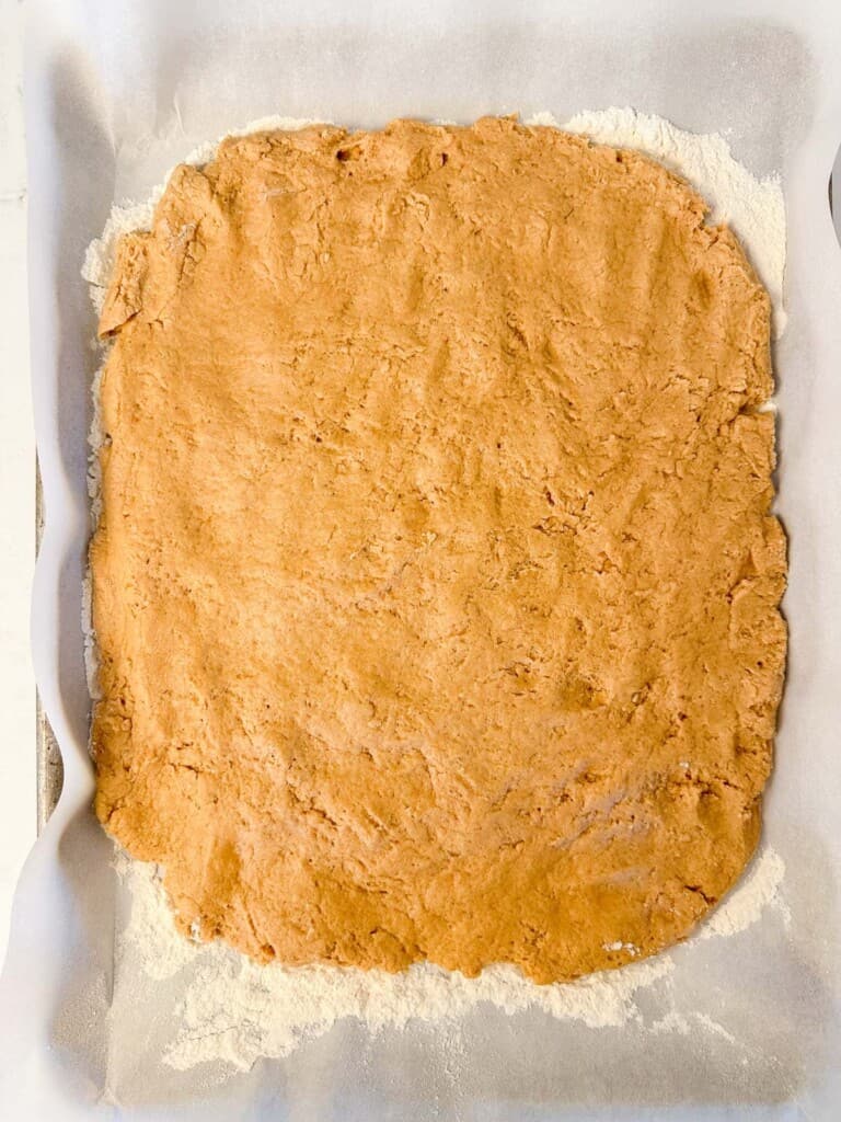 apple cider donut dough pressed out to three quarter inch thickness, preparing to be chilled