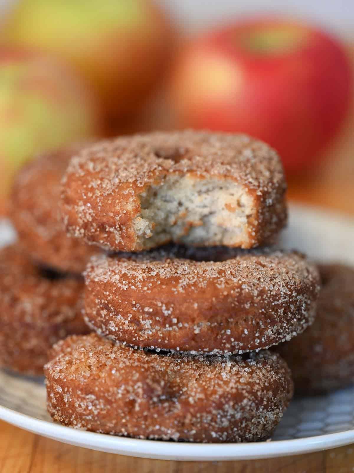 stack of freshly fried apple cider donuts with cinnamon sugar, on a plate