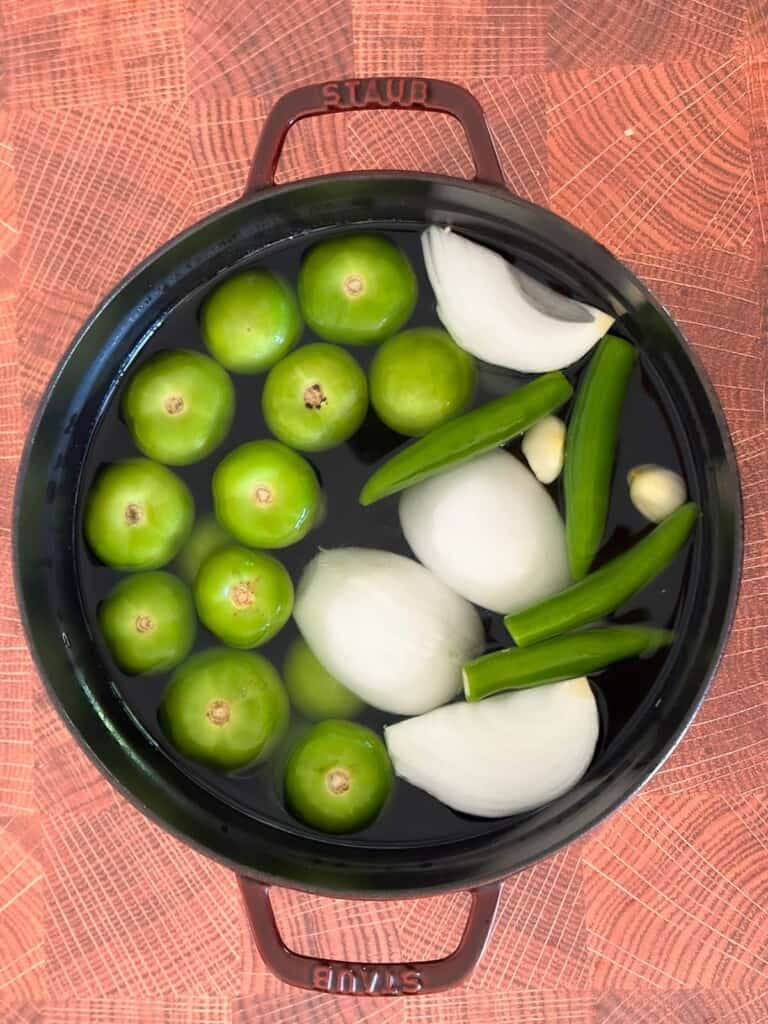 ingredients for salsa verde being boiled in a pan.