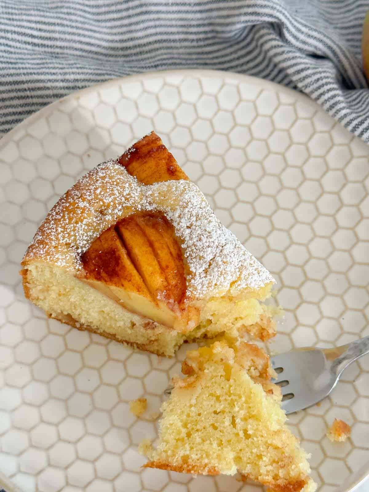 apple cake served on a cute plate with a bite on a fork