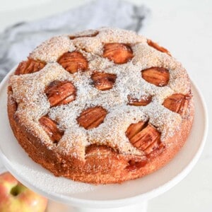 sunken apple cake on a white cake stand