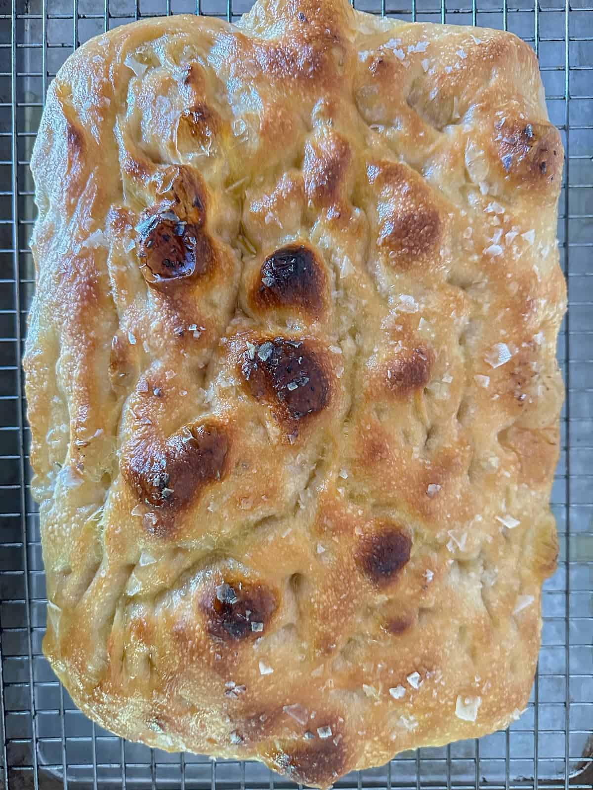 focaccia bread resting on a baking rack after coming out of the oven