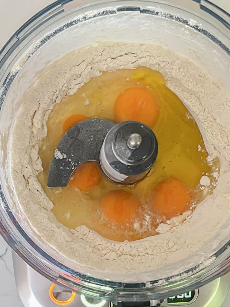 ingredients for homemade pasta in the bowl of a foodprocesser, ready to mix