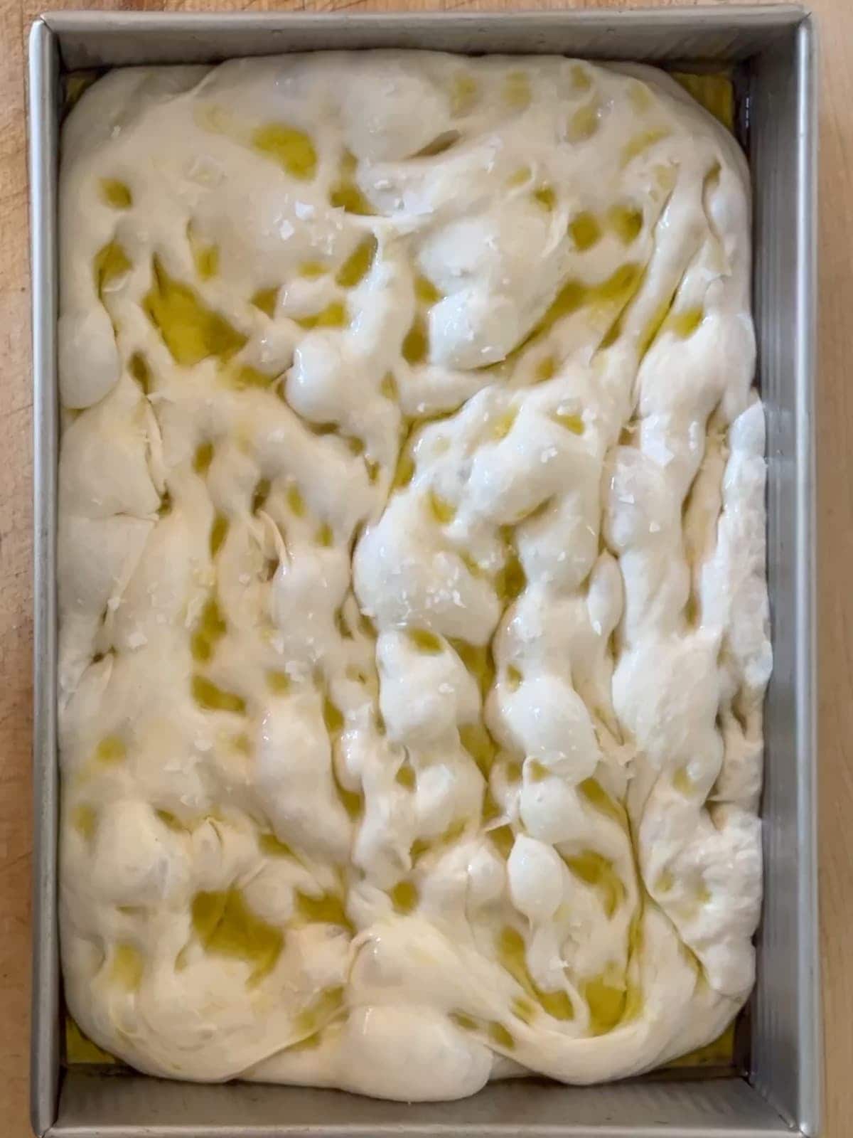 focaccia dough with flakey salt and olive oil added just before baking
