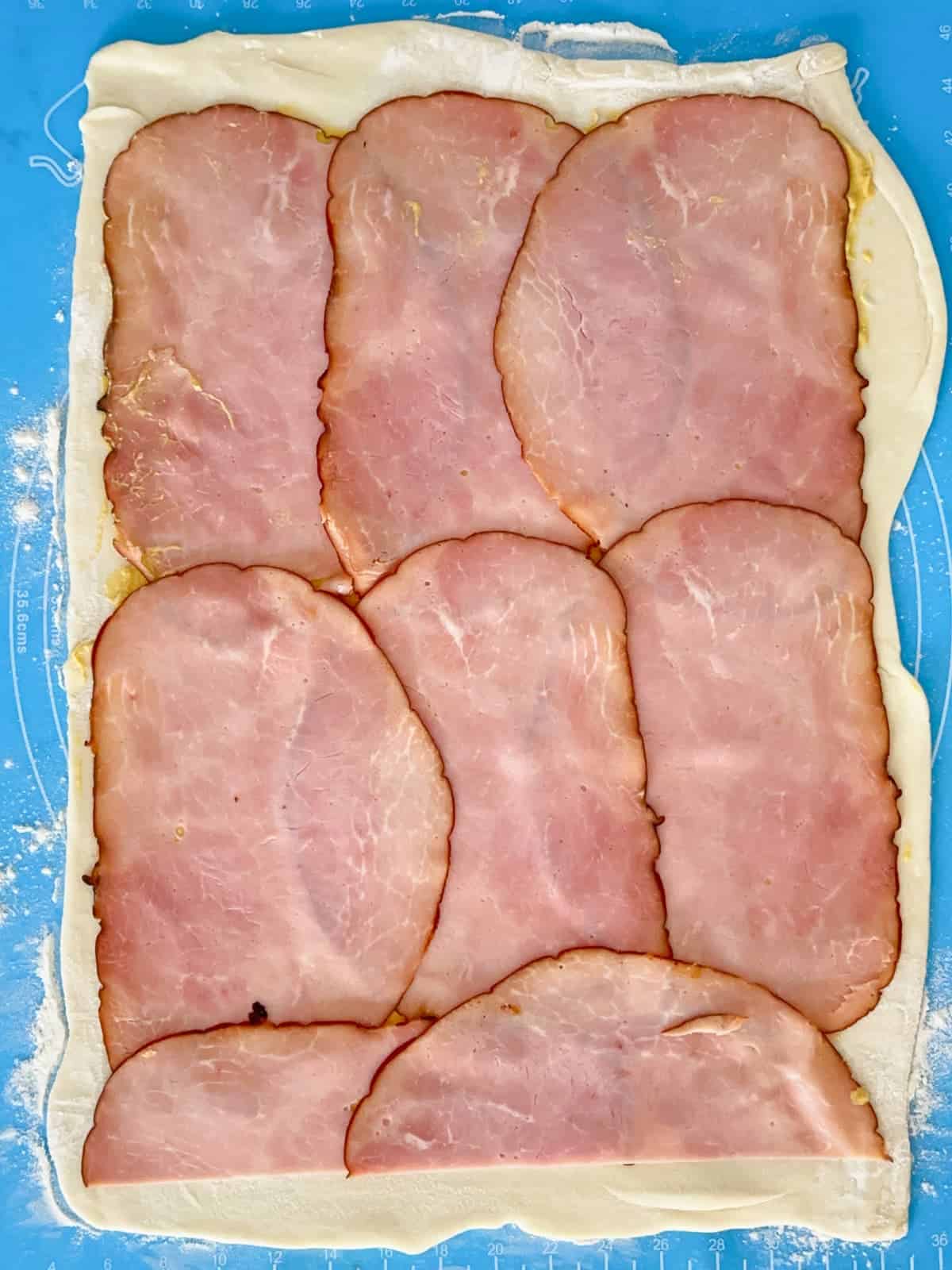 thinly sliced ham laid on top of the mustard