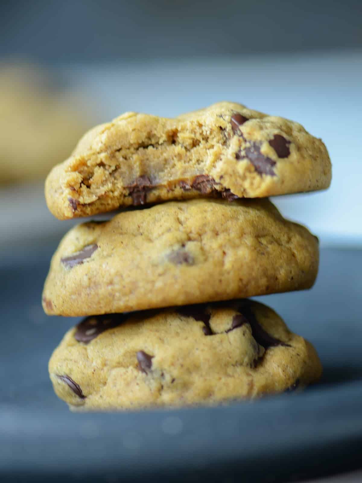 a stack of soft pumpkin chocolate chip cookies with a bite out of the top cookie 