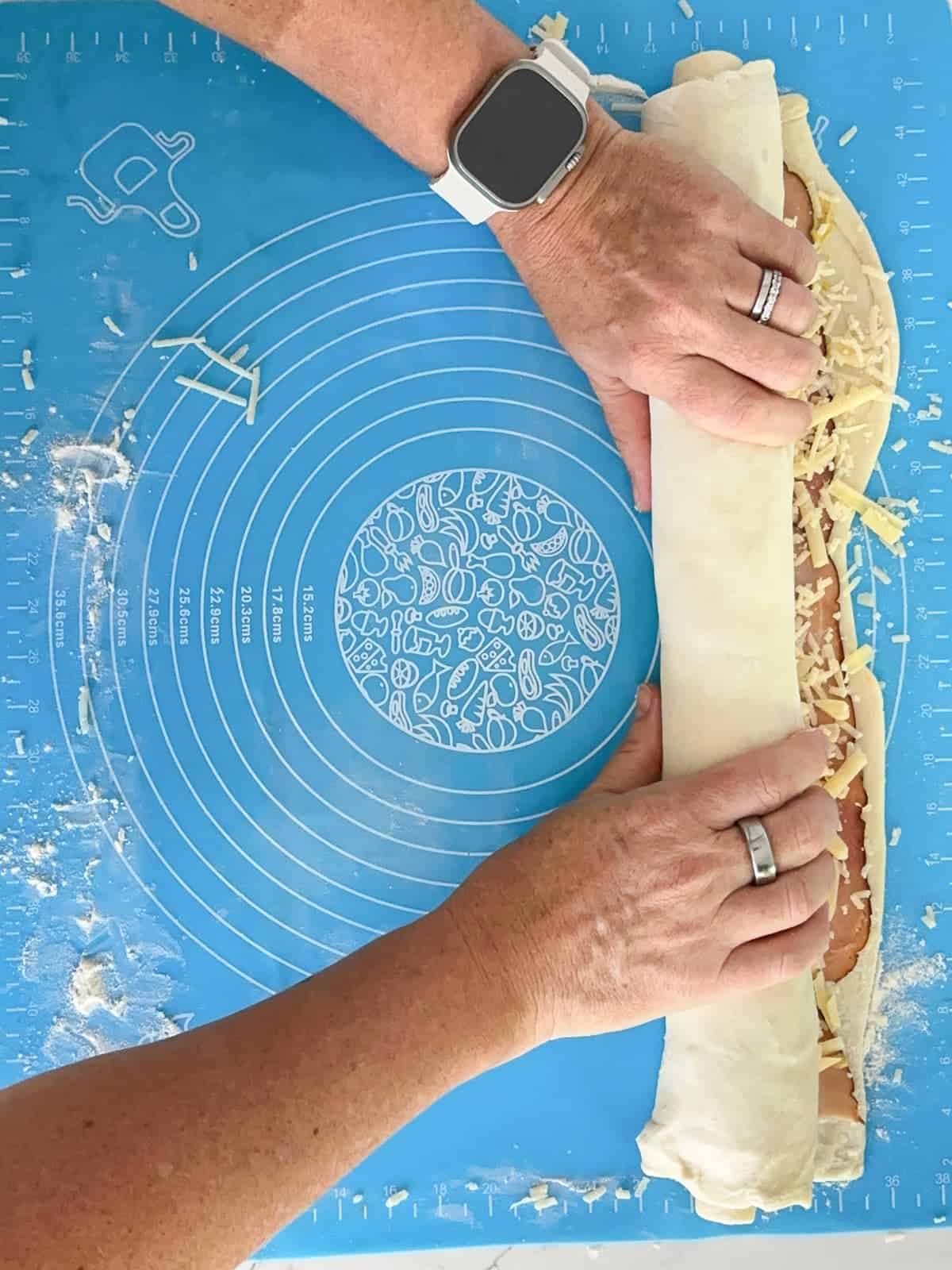 continuing to roll the dough until it is completely rolled into a log