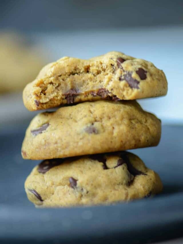 a stack of soft pumpkin chocolate chip cookies with a bite out of the top cookie