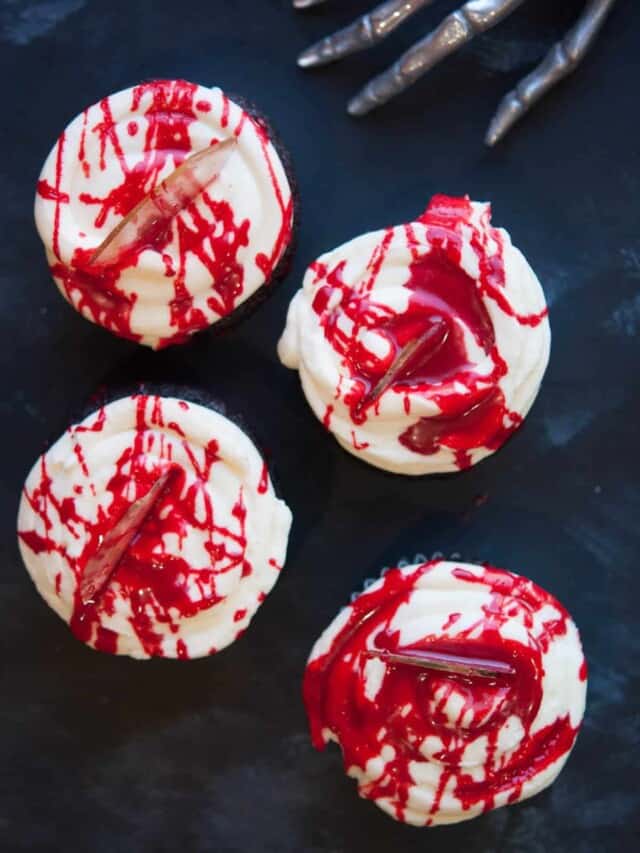 a table of halloween cupcakes with a creepy skeleton hand in view