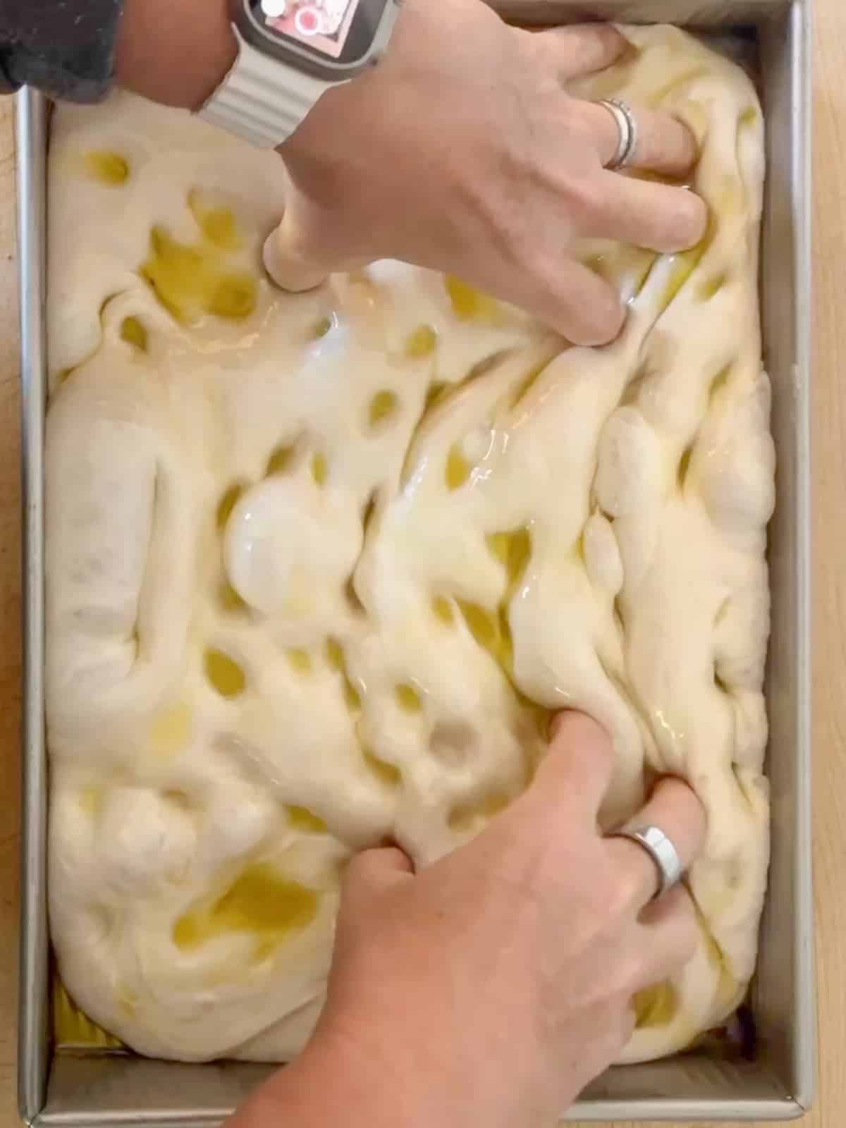 dimpling the focaccia dough with oiled fingers