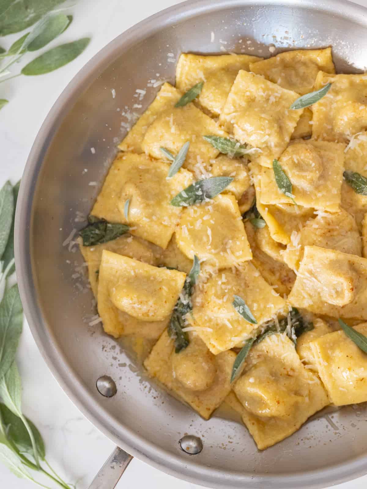 a pan of homemade pumpkin ravioli in a brown butter sage sauce