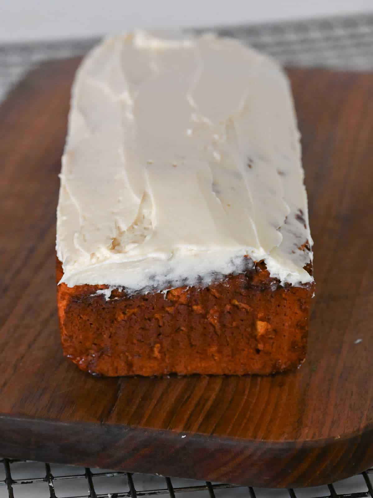 loaf of iced pumpkin bread on a cutting board