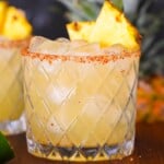 close up of a pineapple margarita with chile lime salt rim
