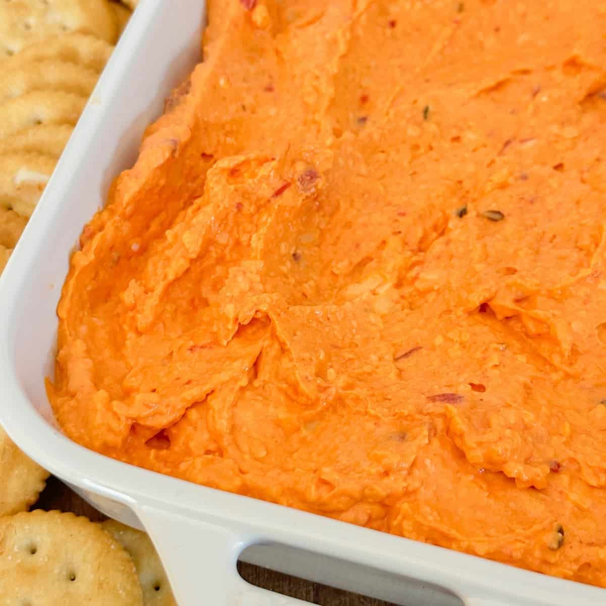 pimento cheese in a white dish surrounded by a pile of ritz crackers