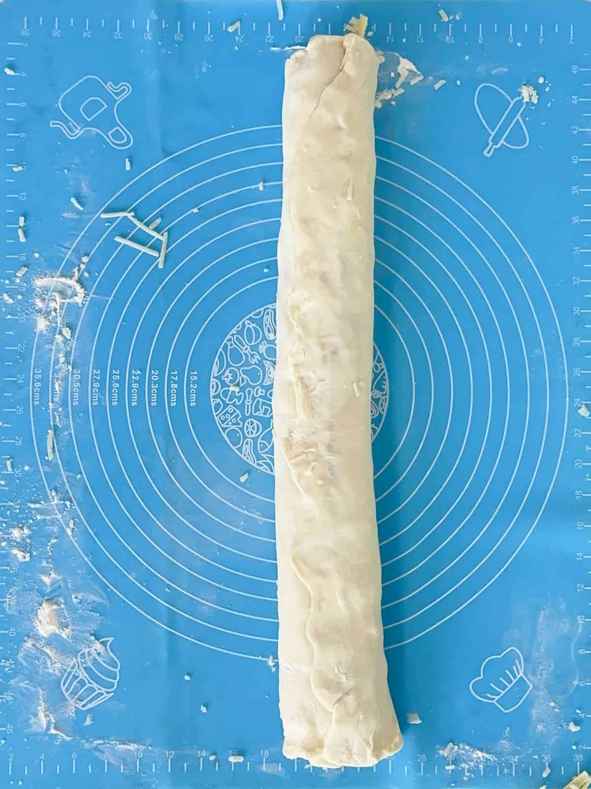 a rolled log of puff pastry dough filled with ham and cheese, sealed