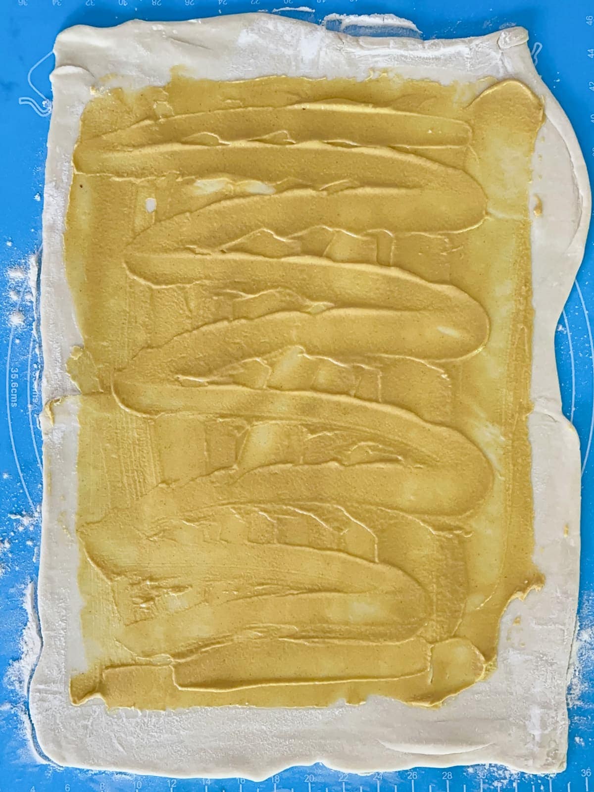 dijon mustard spread with a spatula on puff pastry dough