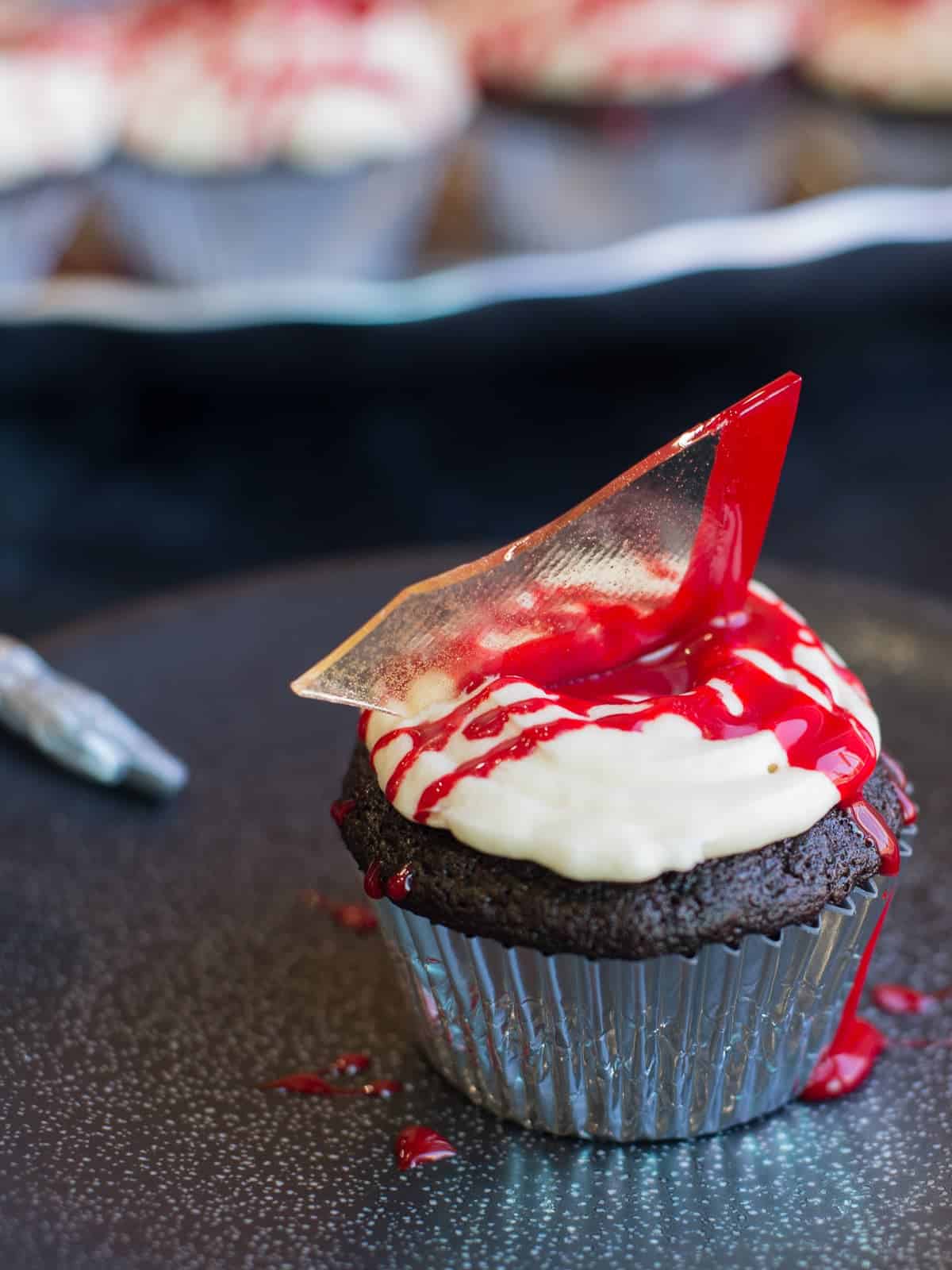 halloween cupcake on a black plate. this cupcake is a chocolote cupcake filled with a luxardo cherry and topped with
