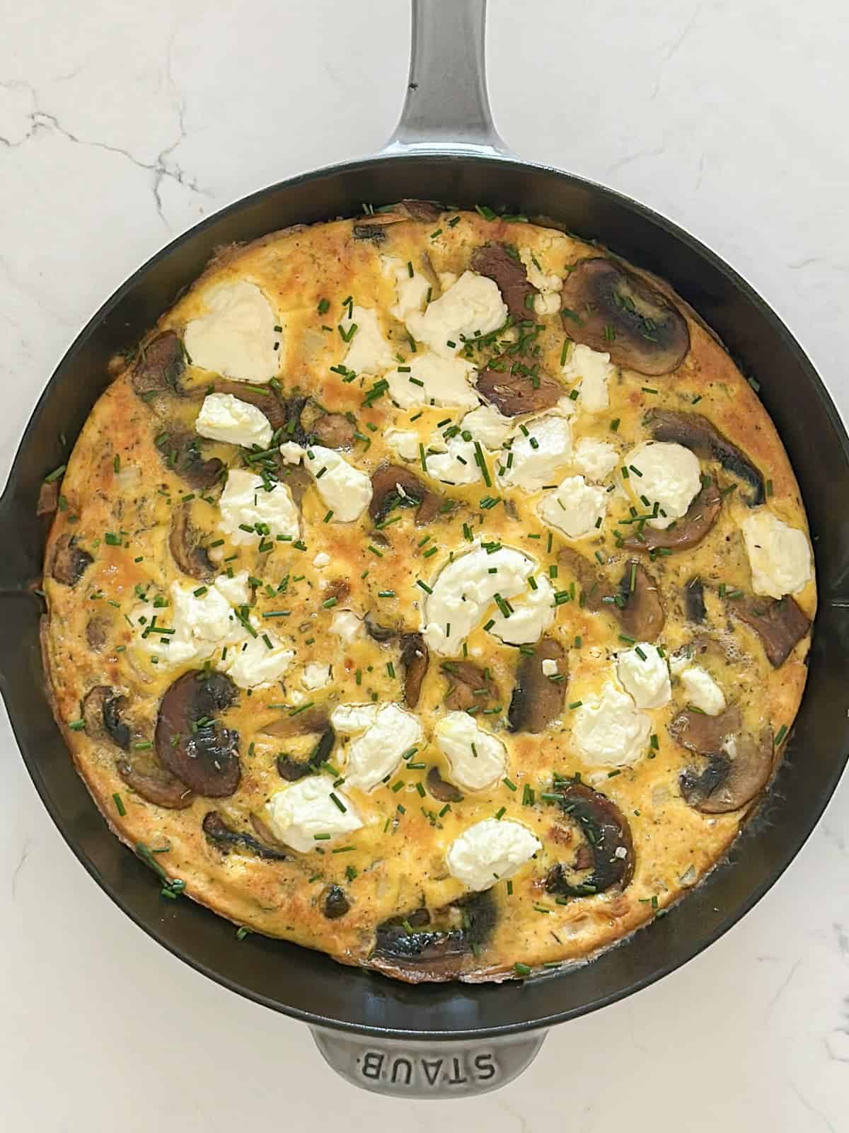 mushroom and goat cheese veggie frittata in a staub enameled cast iron skillet