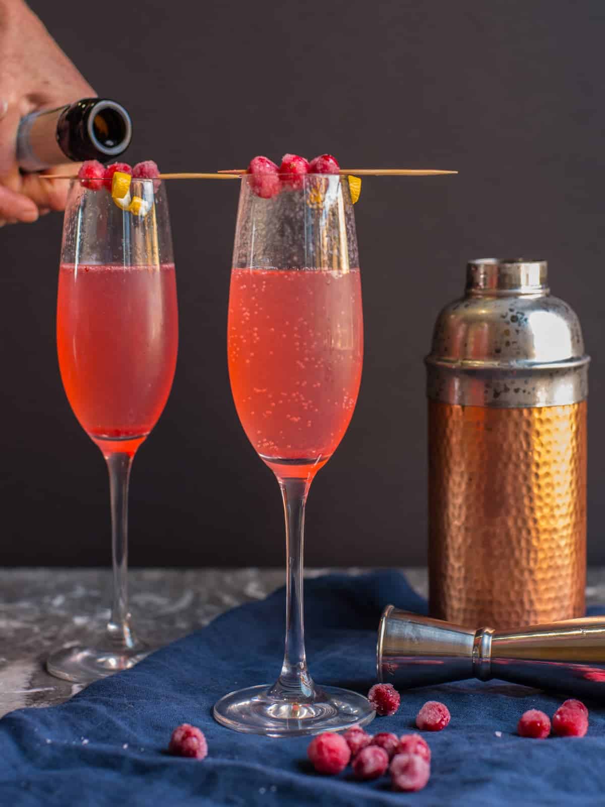 champagne being poured into cranberry cocktails for the holidays