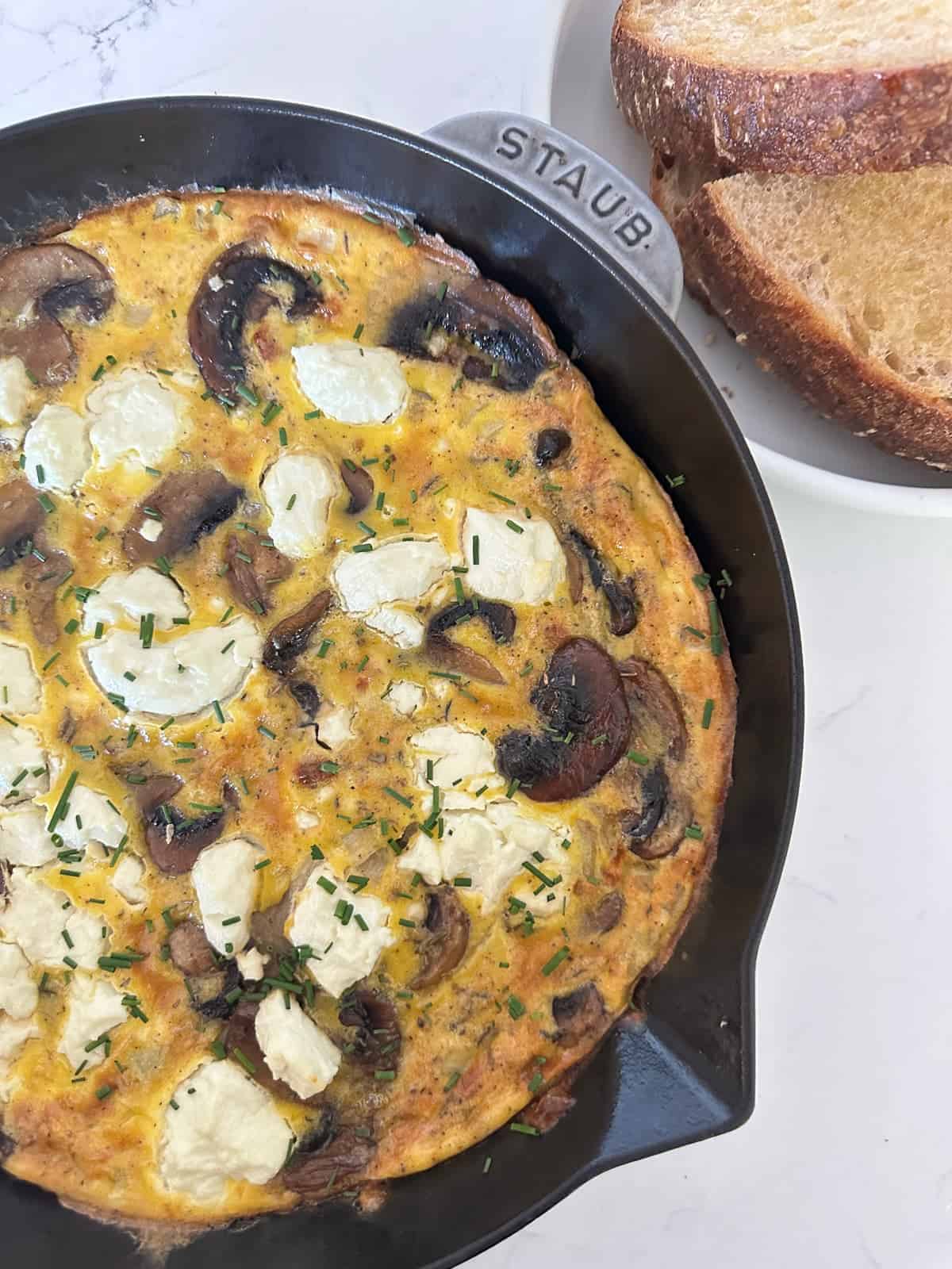 close up af a mushroom and goat cheese veggie frittata in a cast iron pan