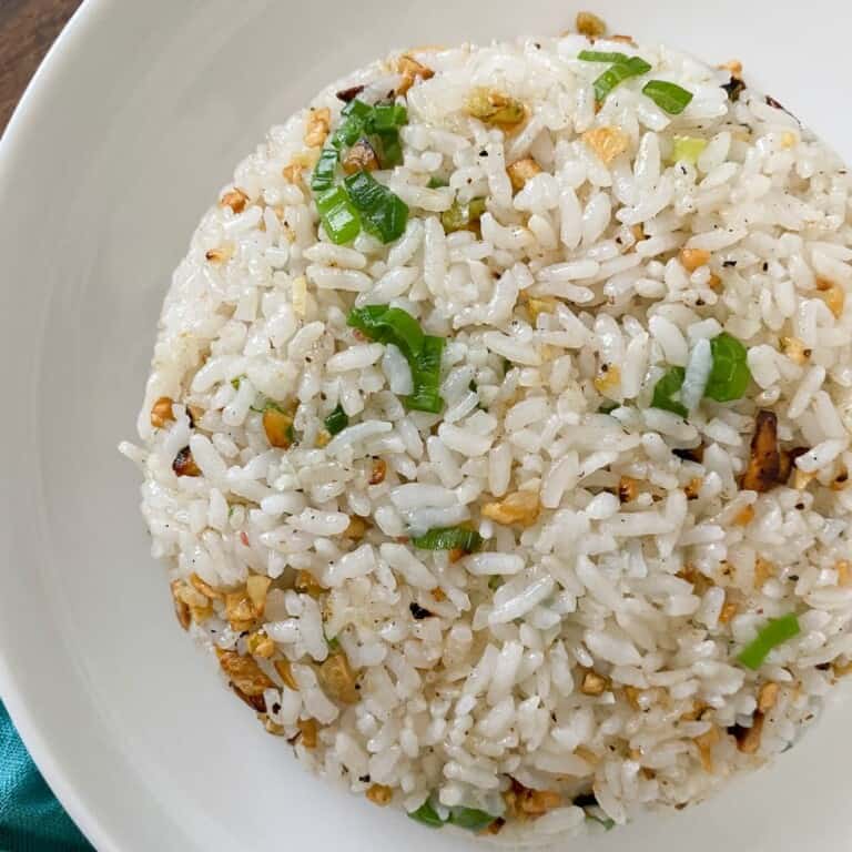 a plate full of garlic fried rice. Topped with green onions