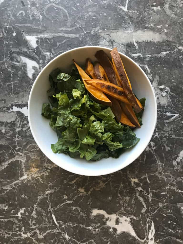 a bowl with greens and sweet potato fires