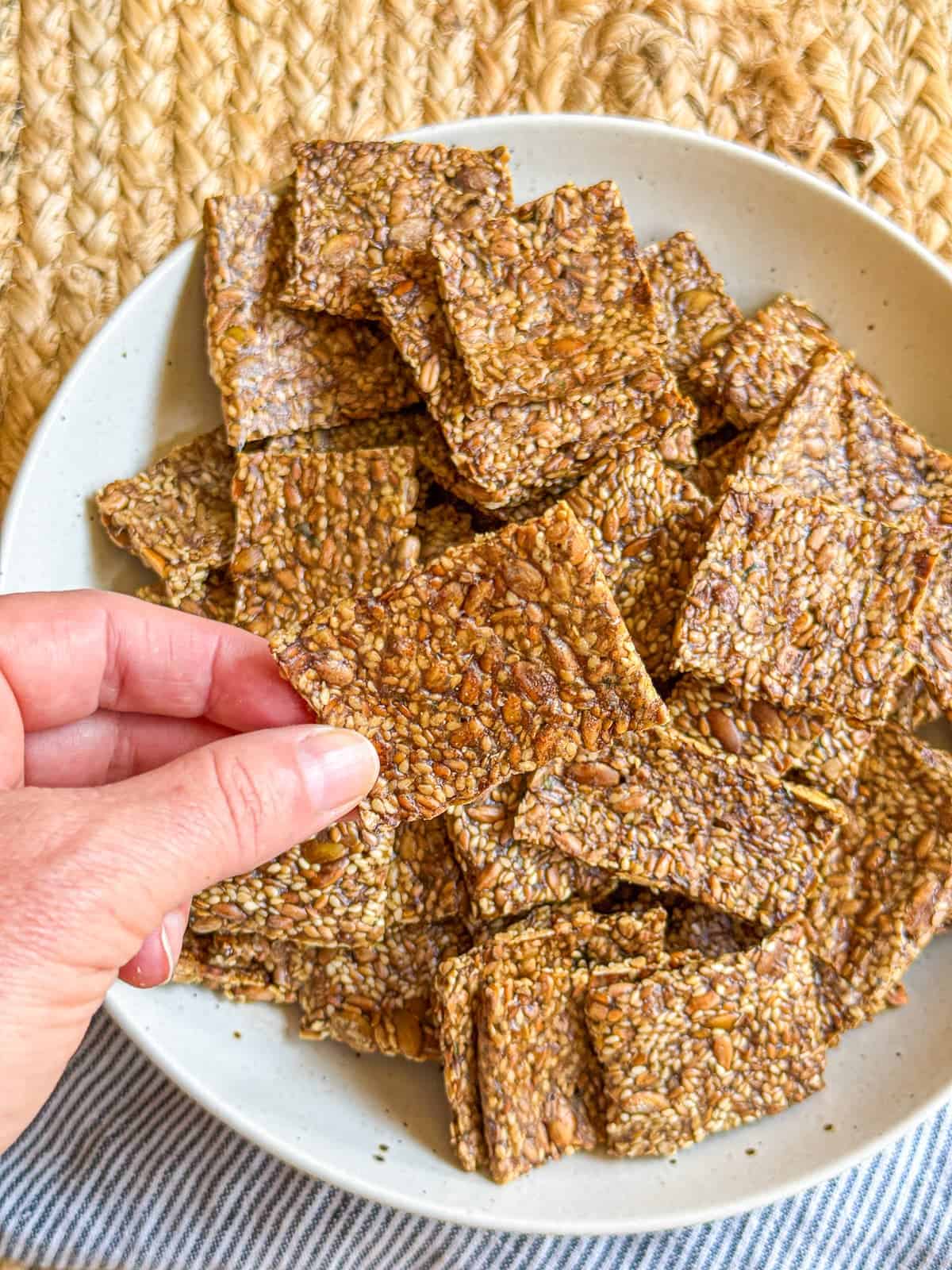 Crispy toasted seed crackers in my hand show close-up details of the seeds