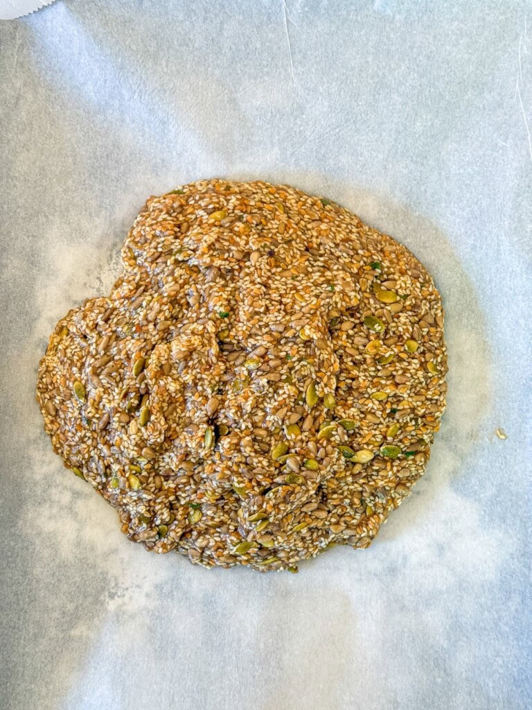 Seed cracker dough on a baking sheet ready to spread