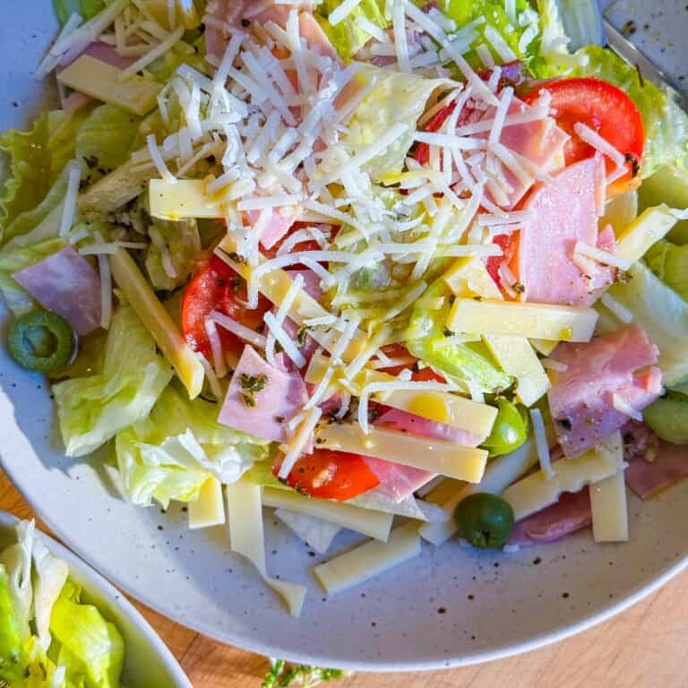 A salad with ham, cheese and tomatoes in a bowl.