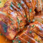 Super easy baked buffalo chicken breasts sliced in a pan with buffalo sauce