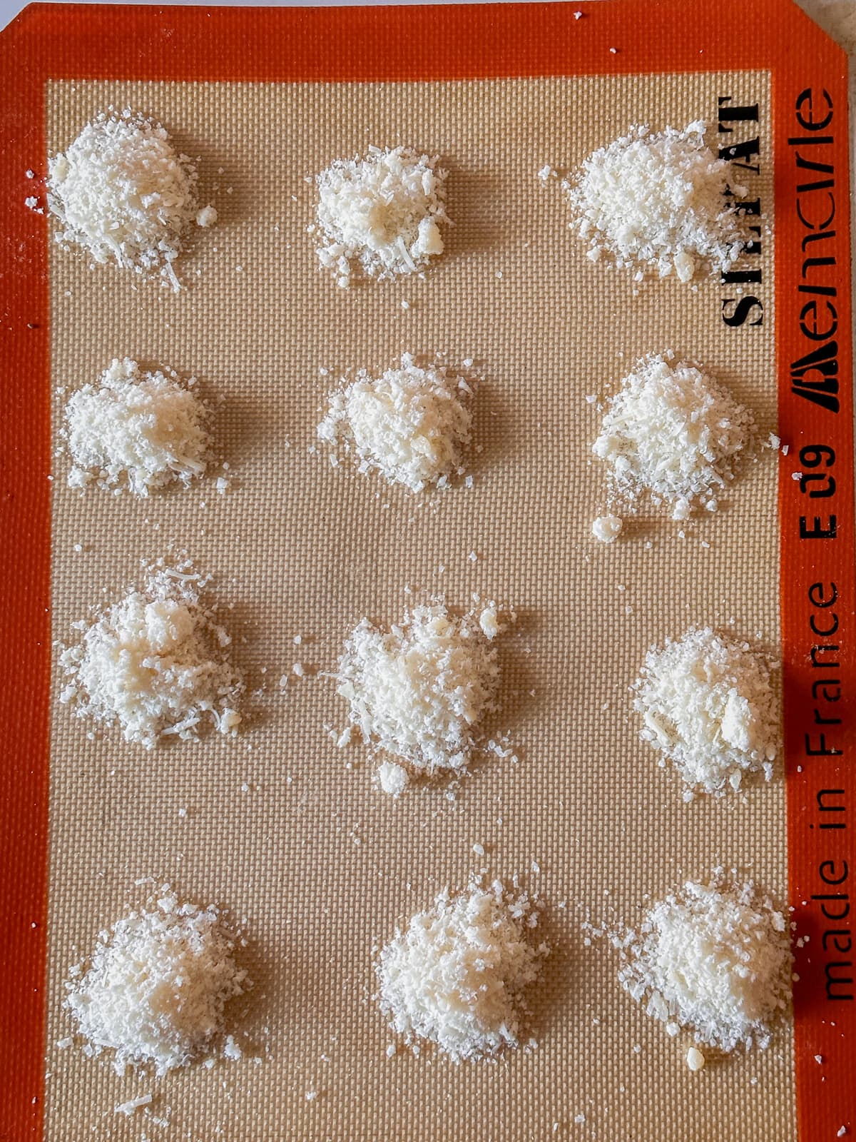 mounds of shredded cheese on a silpat ready to baked into crunchy cheese crisps
